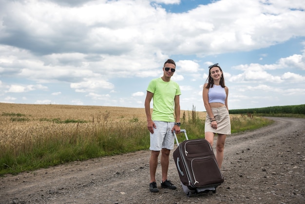 Two beautiful young people enjoy summer time adventure on car