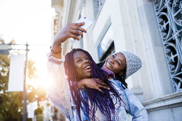 Две красивые молодые женщины, используя мобильный телефон на улице.
