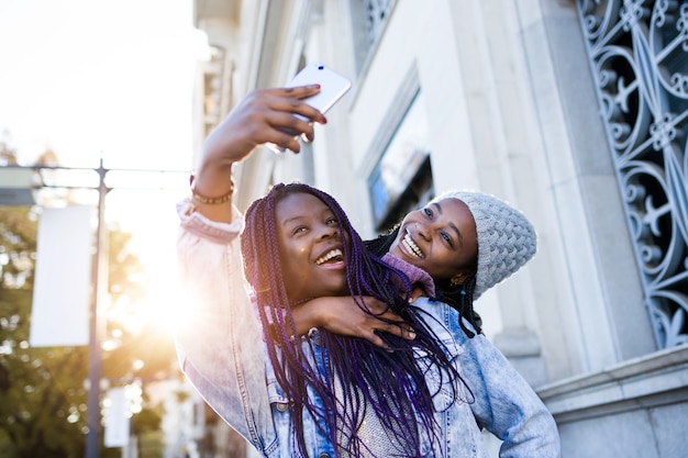 Two beautiful young woman using mobile phone in the street.