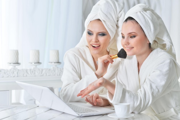 Two beautiful young women in bathrobes sitting at table