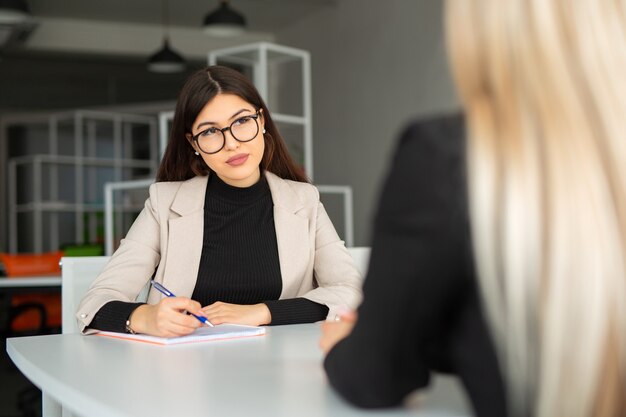 Foto due belle giovani donne in ufficio al tavolo