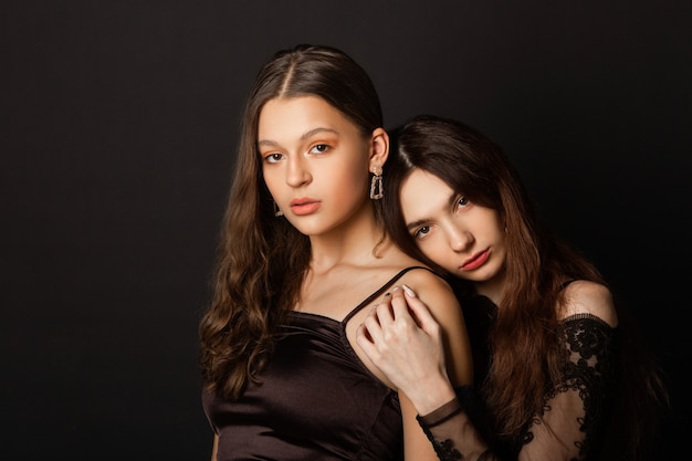 Two beautiful young women with makeup and hairstyle on a black background