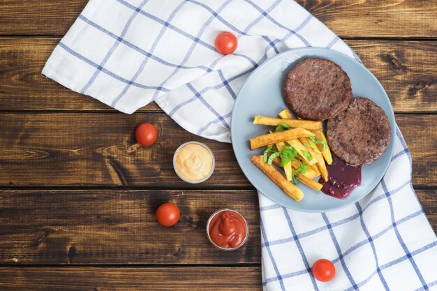 Two beef hamburgers with fries on wooden table