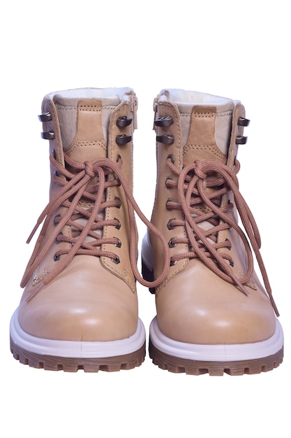 Two beige winter boots with laces stand toes first on a white clipping background.