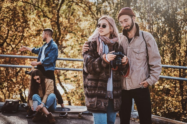 秋の公園で散歩を楽しみながら、2人の親友がフォトカメラで写真を見ています。