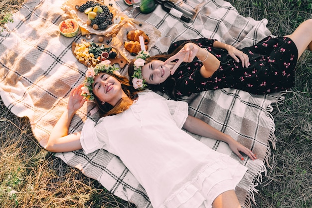 Photo two best friends on picnic in the field laying on the laid smiling top view friendship