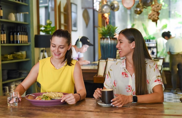 Two best friends talking and eating in a cafe