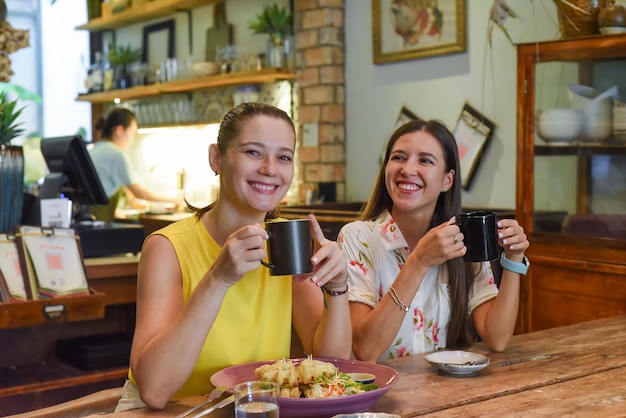 Two best friends talking and eating in a cafe