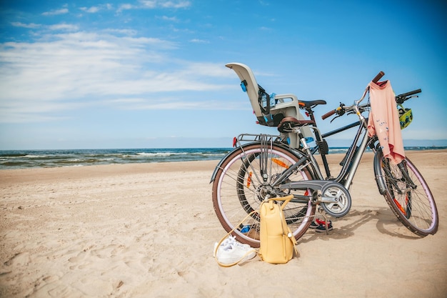 Два велосипеда с детским креслом стоят на пляже