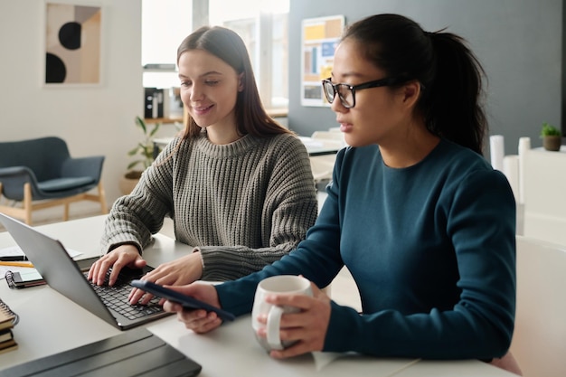 Two biracial women working in office