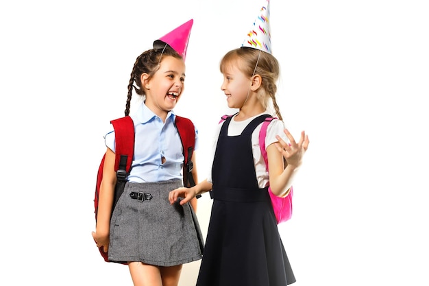 Due ragazze di compleanno in camicia blu uniforme scolastica abiti cappello isolato su sfondo bianco ritratto in studio per bambini. concetto di stile di vita di educazione dei bambini dell'infanzia. mock up spazio di copia