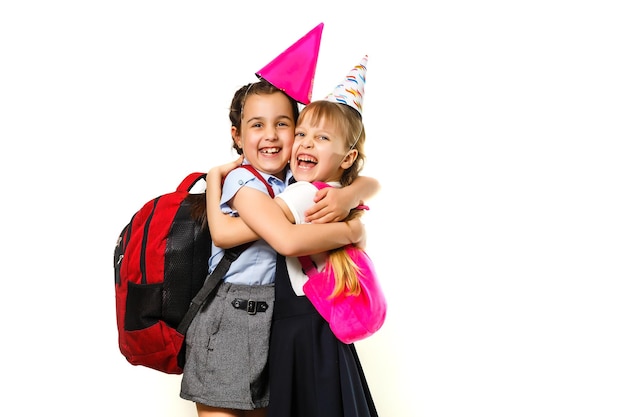 Due ragazze di compleanno in camicia blu uniforme scolastica abiti cappello isolato su sfondo bianco ritratto in studio per bambini. concetto di stile di vita di educazione dei bambini dell'infanzia. mock up spazio di copia