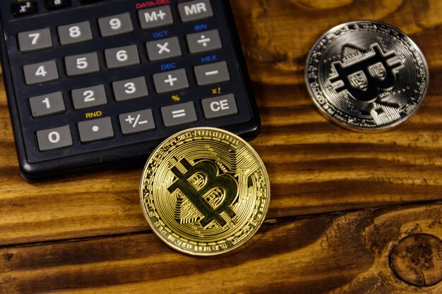 Two bitcoins and calculator on wooden desk