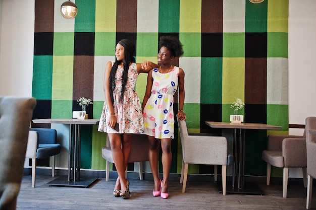 여름 드레스 Higheels에서 두 흑인 아프리카 여자 친구는 카페에서 포즈