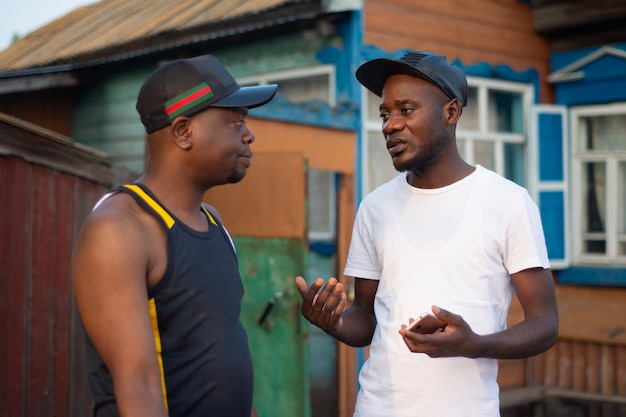 Два чернокожих парня обсуждают вопросы бизнеса на фоне деревенского дома