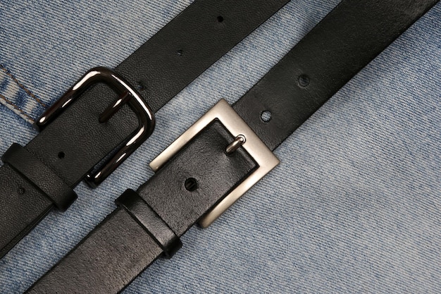 Two black leather belt on a background of jeans