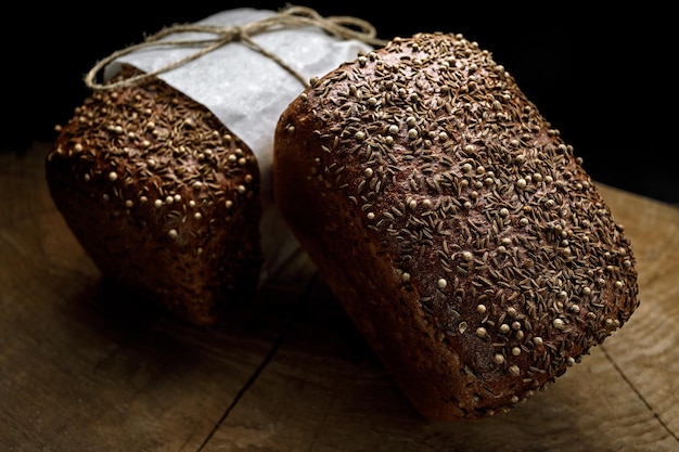 Two black loaves of bread on a wooden board