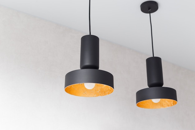 Two black metal pendant lights decorated inside by golden foil