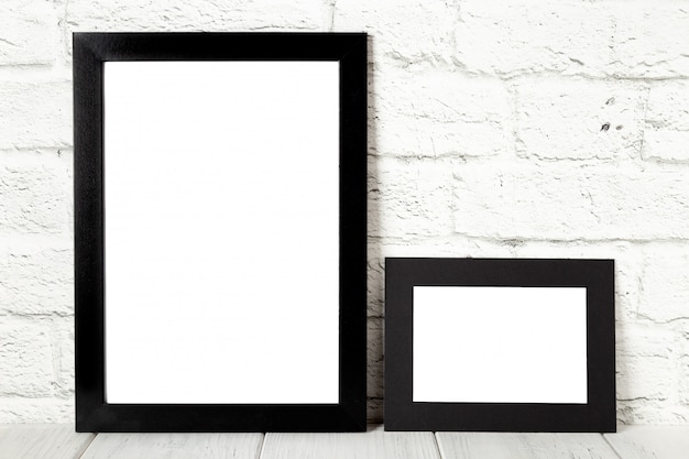 Two black photo frames on wooden table. Mockup with copy space