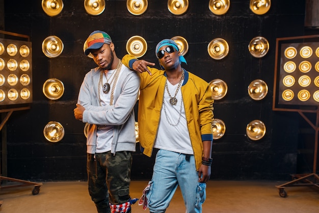 Two black rappers in caps, artists poses on stage