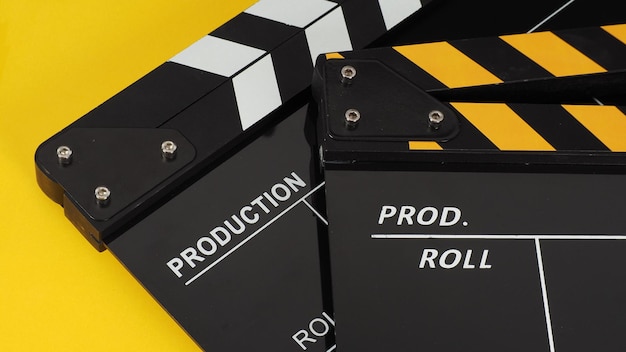 Two black and yellow clapper board or movie slate.it use in video production ,film, cinema industry on yellow background.