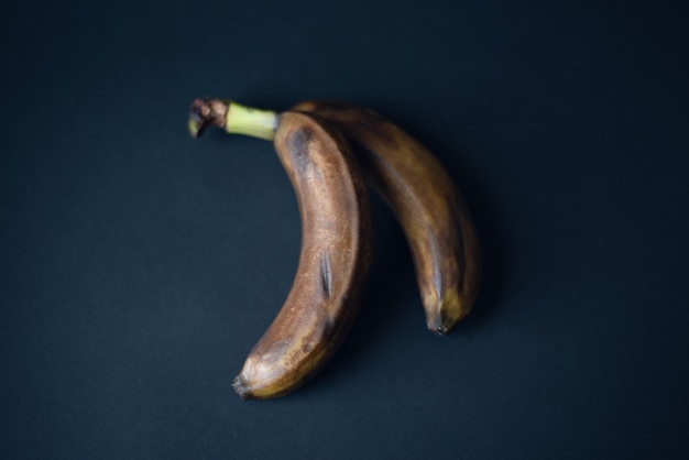 two blackened bananas on a dark background