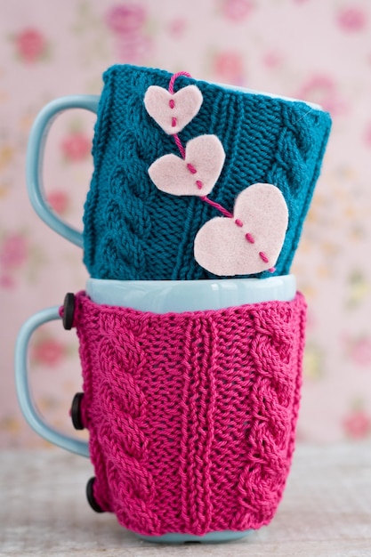 Two blue cups in blue and pink sweater with felt hearts