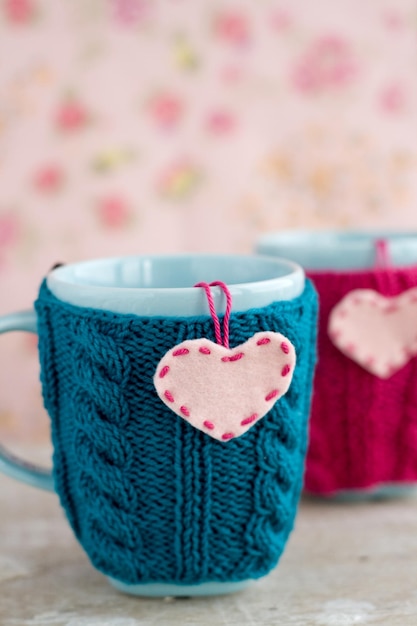 Two blue cups in blue and pink sweater with felt hearts