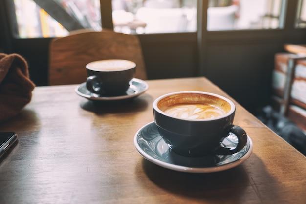 two blue cups of hot latte coffee on wooden table in cafe