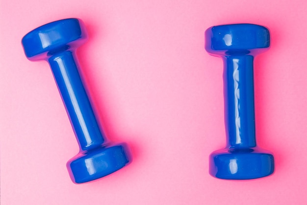 Photo two blue of dumbbells isolated on pink background