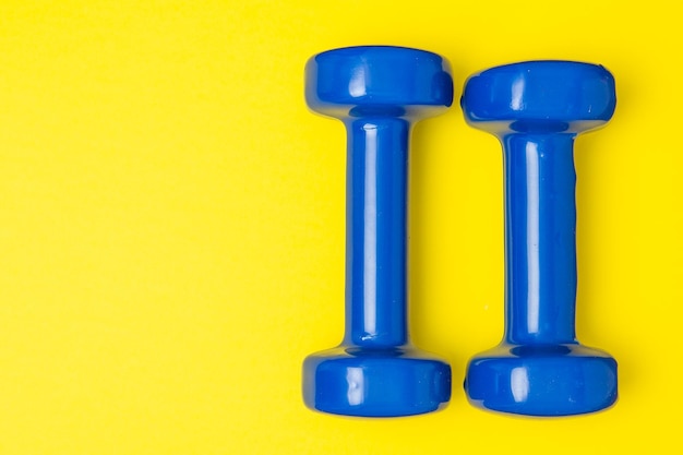 Two blue of dumbbells Isolated on yellow background