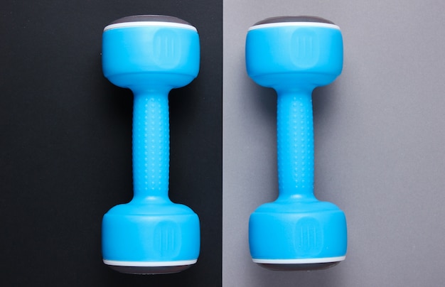 Photo two blue plastic dumbbells on a gray-black table. top view