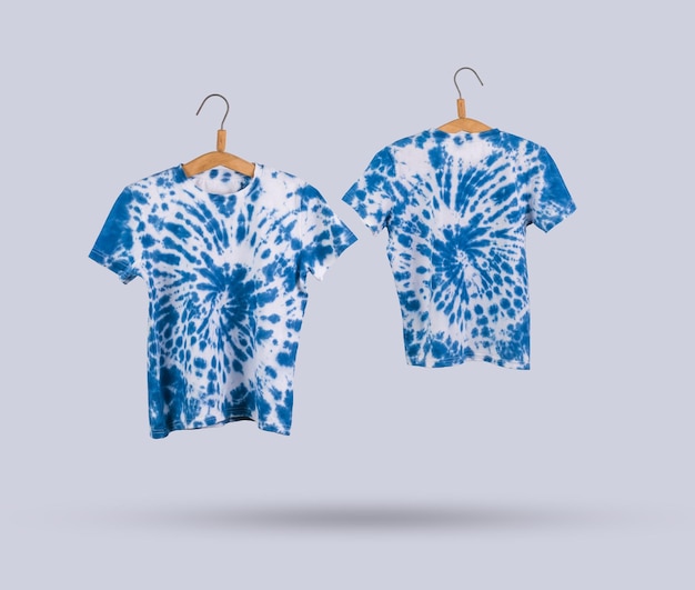 Due magliette tie dye blu su grucce su sfondo chiaro