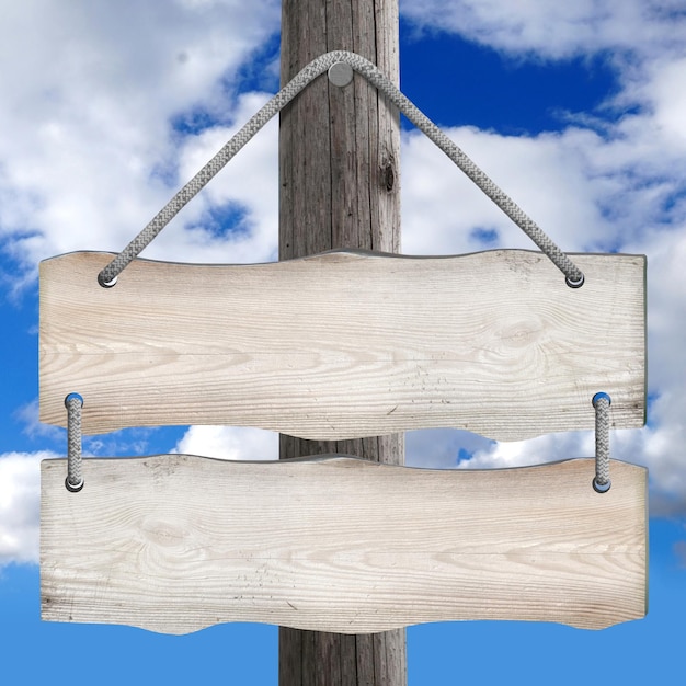 Two boards hanging on post on ropes with sky in background