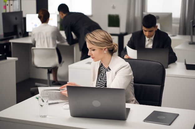 Two bookshop managers working on laptop in a large bright office. Business dress code