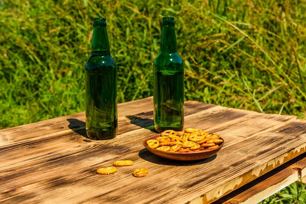 Due bottiglie di birra e piatto di ceramica con salatini salati su tavola in legno rustico