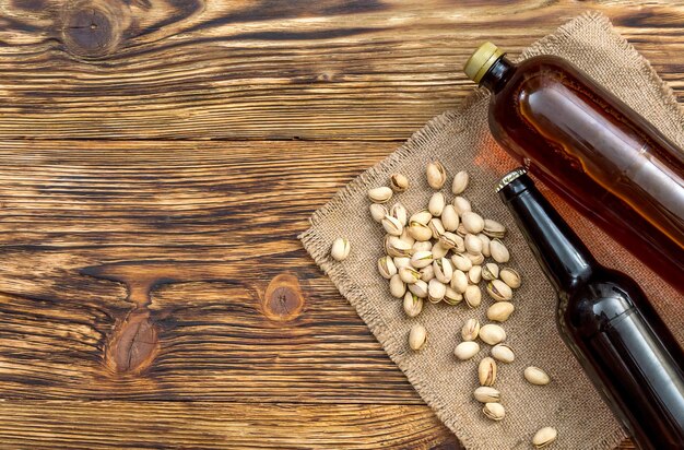 Two bottle of beer with pistachios on the table Top view