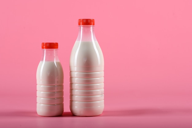 Two bottle of milk on a pink background.