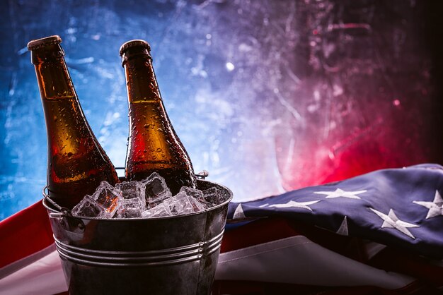 Due bottiglie di birra in un secchiello del ghiaccio con la bandiera americana che giace nelle vicinanze. concetto di celebrazione del giorno dell'indipendenza