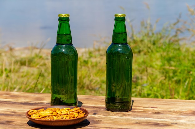 Two bottles of beer on wooden table near a river