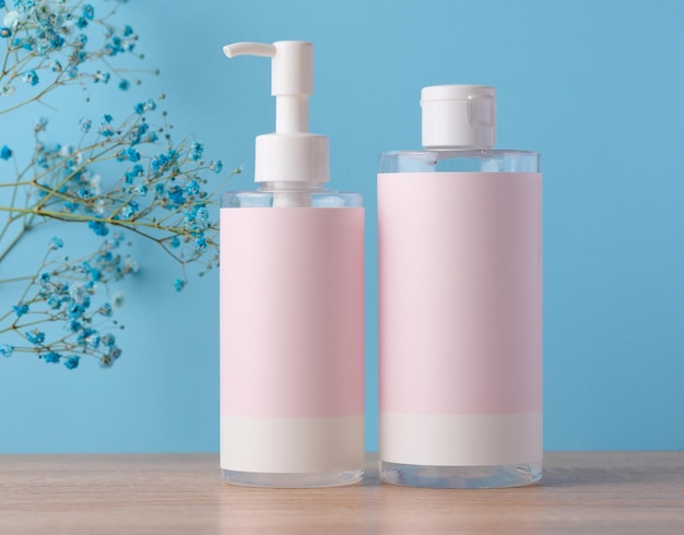 Two bottles for cosmetics with a pink paper label on a blue background Bottle for tonic gel