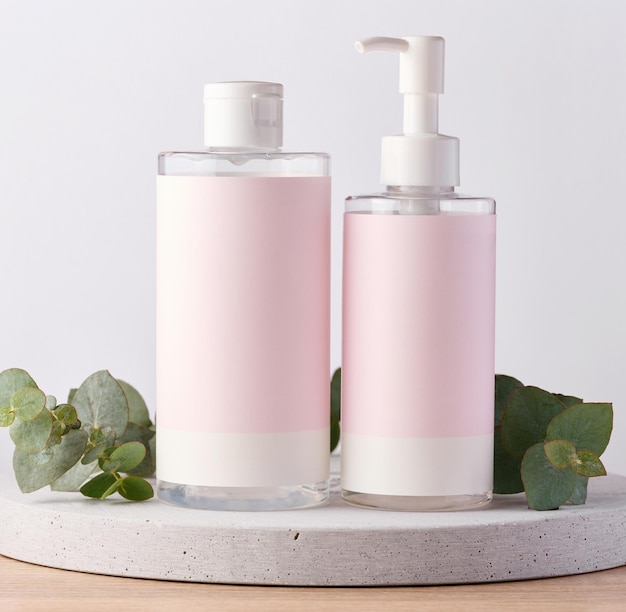 Two bottles for cosmetics with a pink paper label on a white background