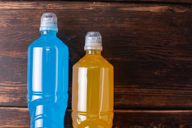 Two bottles of orange and blue on a dark wooden background, restoring water and salt balance after sports training, close up