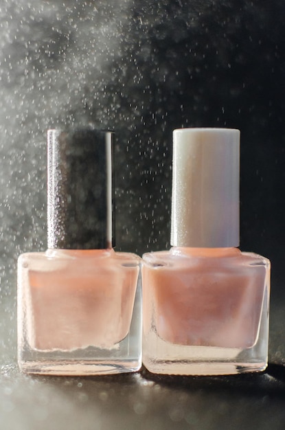 Two bottles of pink nail polish stand side by side on the table