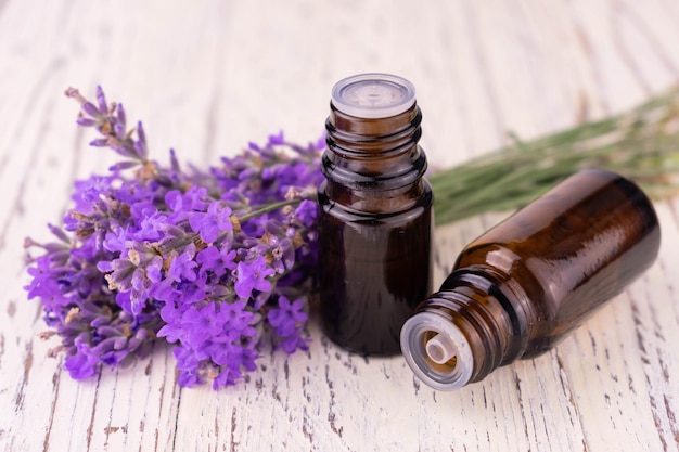 Due bottiglie con olio di lavanda profumato e delicati fiori di lavanda su sfondo bianco