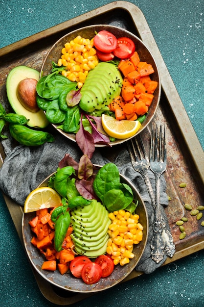 two bowl dish with pumpkin avocado cherry tomatoes green salad and corn on a metal tray healthy balanced eating