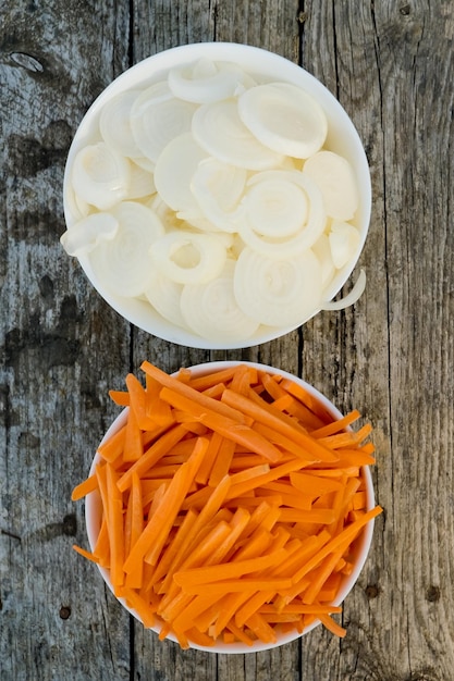 Two bowl full of orange carrot sticks and sliced white onion Close up Selective focus Top view