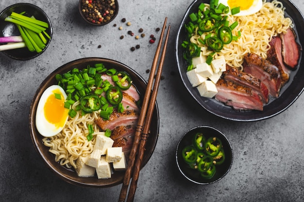 회색 소박한 콘크리트 배경에 고기 국물, 두부, 돼지고기, 달걀 노른자가 있는 맛있는 아시아 누들 수프 라면 두 그릇이 닫혀 있습니다. 저녁 식사 아시아 스타일을 위한 뜨거운 맛있는 일본 라면 수프 | 프리미엄 회색 소박한 콘크리트 배경에 고기 국물, 두부, 돼지고기, 달걀 노른자가 있는 맛있는 아시아 누들 수프 라면 두 그릇이 닫혀 있습니다. 저녁 식사 아시아 스타일을 위한 뜨거운 맛있는 일본 라면 수프 | 프리미엄