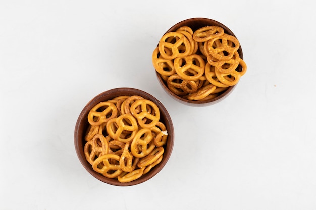 Two bowls of tasty crunchy pretzels on white surface