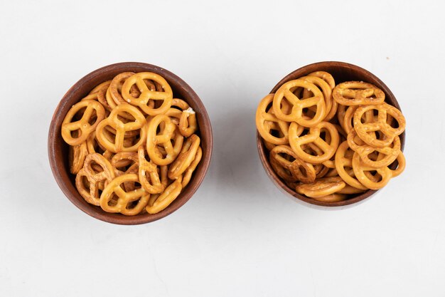 Two bowls of tasty crunchy pretzels on white surface